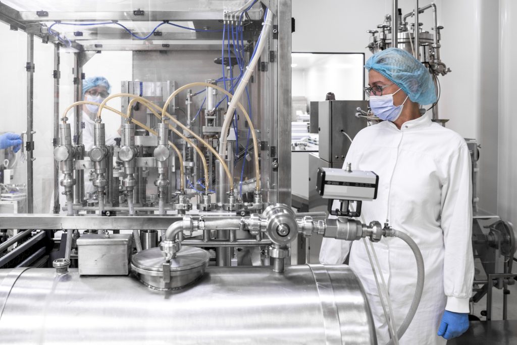 Technician monitoring a sterile aseptic filling line in a biopharmaceutical manufacturing facility